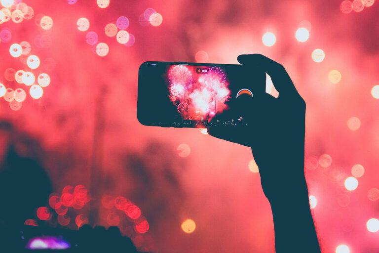 Jemand fotografiert mit dem Handy ein Feuerwerk als Into für einen Artikel zum Thema 'Jahresrückblick'