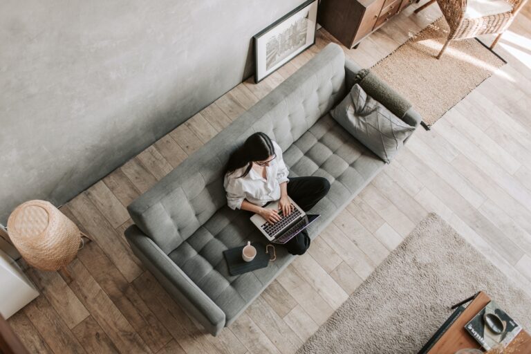 Eine Frau sitzt auf dem Sofa zuhause und arbeitet als Beispiel für Remote Work