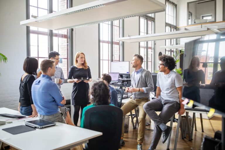 Das Titelbild für den Beitrag 'Effektive Kommunikation für Führungskräfte' zeigt eine Gruppe an Menschen im Büro bei einem Meeting