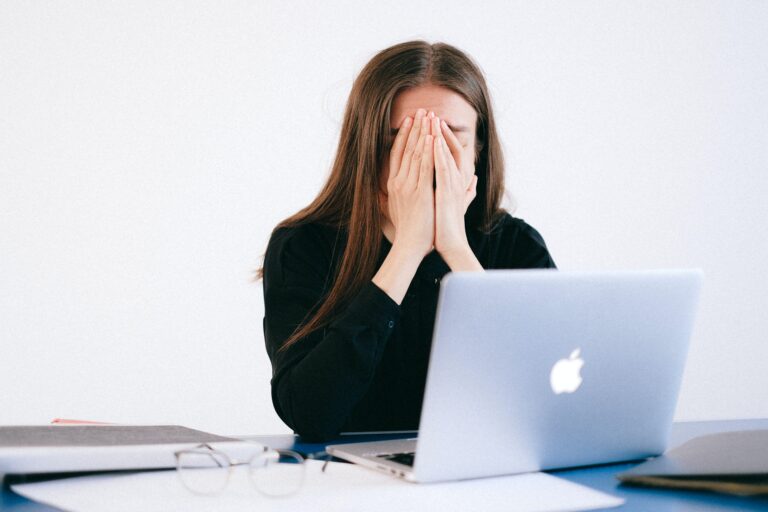 Eine Frau sitzt verzweifelt vor ihrem Laptop, weil sie jemanden entlassen muss.