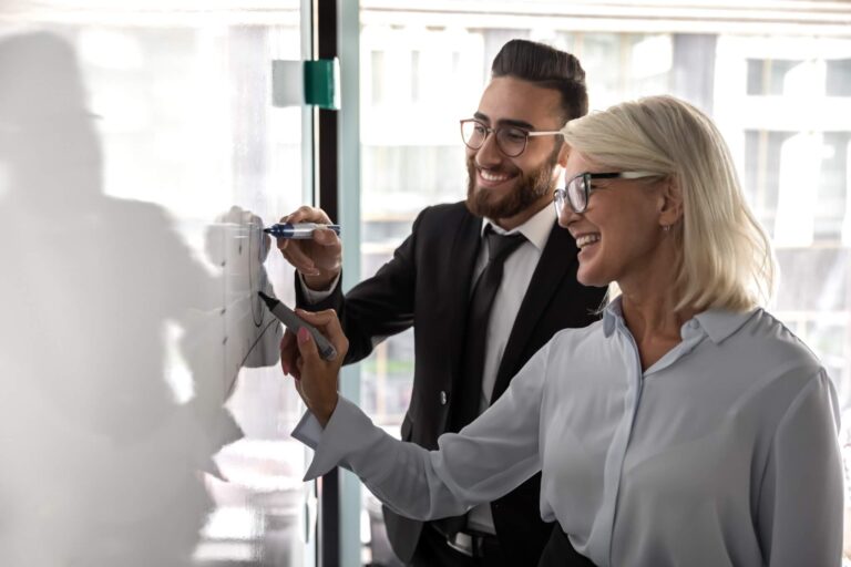 Eine Frau und ein Mann am Whiteboard als Einleitung für den Blogpost 'Sei ein Coach und nicht der Experte'